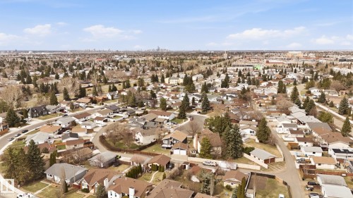 Residential neighborhood featuring a curvilinear street layout, mature trees, and a distant city skyline - 1729 65 Street, Edmonton, AB - Outdoor With View