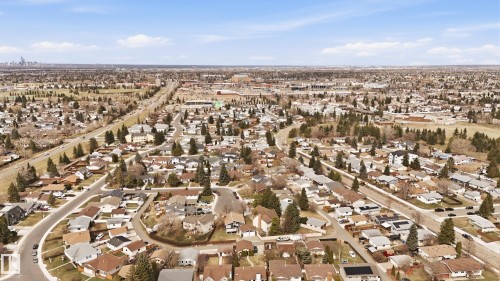 Aerial perspective showcasing a residential neighborhood with numerous single-family homes, mature trees, and a visible roadway - 1729 65 Street, Edmonton, AB - Outdoor With View