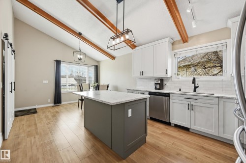 Kitchen featuring a two-tone island with a light-toned countertop, stainless steel appliances, and wood-finish flooring - 1729 65 Street, Edmonton, AB - Indoor Photo Showing Kitchen With Stainless Steel Kitchen