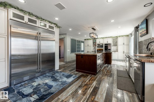 Spacious kitchen with wood-finish flooring, white cabinetry, recessed lighting, and a large stainless steel refrigerator - 7 Doolan Place, St. Albert, AB - Indoor Photo Showing Kitchen With Upgraded Kitchen