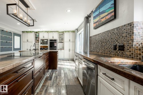 Spacious kitchen with wood-finish flooring and a central island featuring an integrated sink and cooktop - 7 Doolan Place, St. Albert, AB - Indoor Photo Showing Kitchen
