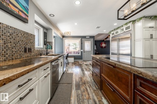 Functional kitchen featuring a central island, stainless steel refrigerator, and integrated cooktop - 7 Doolan Place, St. Albert, AB - Indoor Photo Showing Kitchen With Upgraded Kitchen