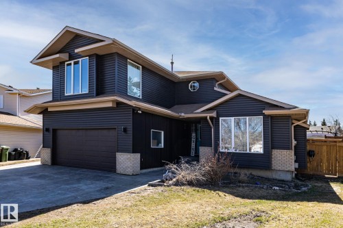 Two-story residence featuring dark horizontal siding, light soffits, and a brown asphalt shingle roof - 7 Doolan Place, St. Albert, AB - Outdoor