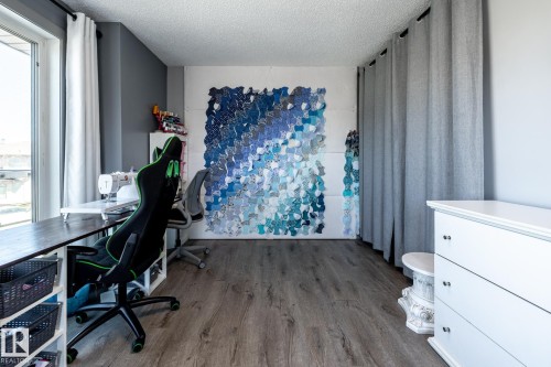 Spacious room featuring wood-finish flooring, a large window with white curtains, and a textured accent wall - 7 Doolan Place, St. Albert, AB - Indoor Photo Showing Office