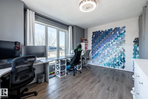 Room featuring wood-finish flooring, a contemporary ceiling light fixture, and large windows providing abundant natural light - 7 Doolan Place, St. Albert, AB - Indoor Photo Showing Office
