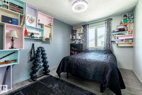 Bedroom featuring wood-finish flooring, a contemporary ceiling light fixture, and a window with white trim - 7 Doolan Place, St. Albert, AB - Indoor Photo Showing Bedroom