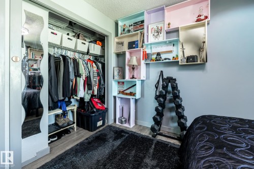 Closet with mirrored sliding door, built-in shelving, and wood-finish flooring - 7 Doolan Place, St. Albert, AB - Indoor