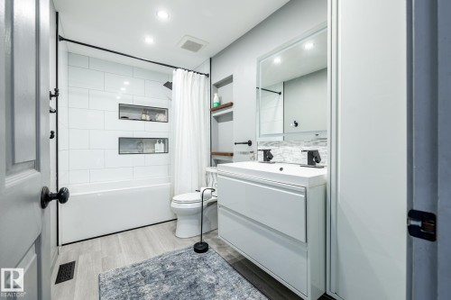 Contemporary bathroom featuring a white vanity with dual sinks, matte black fixtures, and a subway-tiled tub/shower combo with recessed shelving - 7 Doolan Place, St. Albert, AB - Indoor Photo Showing Bathroom