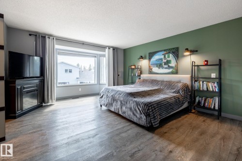 Spacious room featuring wood-finish flooring, a wide window with a deep sill, and an accent wall - 7 Doolan Place, St. Albert, AB - Indoor Photo Showing Bedroom