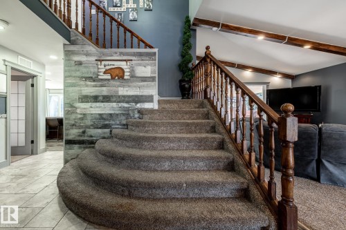 Curved staircase with carpeted treads and carved wood banister - 7 Doolan Place, St. Albert, AB - Indoor Photo Showing Other Room