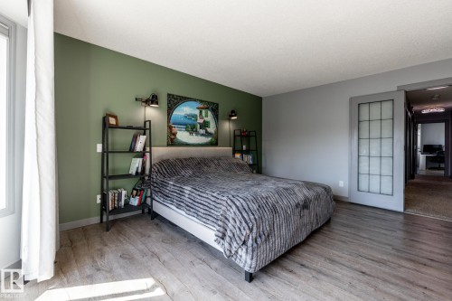 Wood-finish flooring throughout, complemented by a large window with white drapery - 7 Doolan Place, St. Albert, AB - Indoor Photo Showing Bedroom