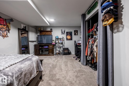 Carpeted room featuring recessed lighting, a built-in media console, a floor-length mirror, and a closet with curtain enclosure - 7 Doolan Place, St. Albert, AB - Indoor