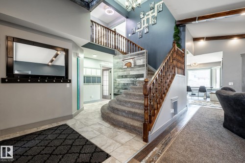 Grand entryway featuring a curved staircase with wood balusters, tile flooring, and a decorative shiplap wall accent - 7 Doolan Place, St. Albert, AB - Indoor Photo Showing Other Room