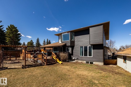 Expansive backyard featuring a multi-level wood deck, a pergola structure, a fire pit area, and mature evergreen trees - 7 Doolan Place, St. Albert, AB - Outdoor With Exterior