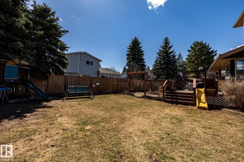 Spacious backyard featuring a multi-level wood deck, pergola, privacy fencing, and mature trees - 7 Doolan Place, St. Albert, AB - Outdoor