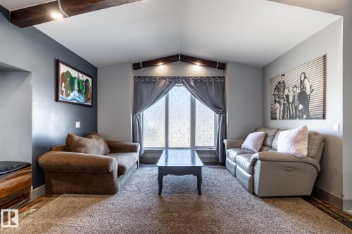 Living area featuring a vaulted ceiling with exposed wood beams, recessed lighting, and a large central window - 7 Doolan Place, St. Albert, AB - Indoor Photo Showing Living Room