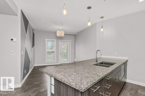 Kitchen island featuring a double basin stainless steel sink, gooseneck faucet, and stone countertop - 204 10126 144 Street, Edmonton, AB - Indoor Photo Showing Kitchen With Double Sink With Upgraded Kitchen