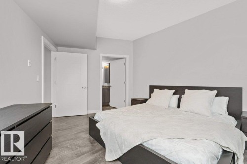 Spacious room featuring light gray walls, wood-finish flooring, and bright overhead lighting - 204 10126 144 Street, Edmonton, AB - Indoor Photo Showing Bedroom