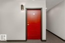 Entry door featuring a vibrant red finish with horizontal panel detailing and brushed nickel hardware - 204 10126 144 Street, Edmonton, AB  - Indoor Photo Showing Other Room 