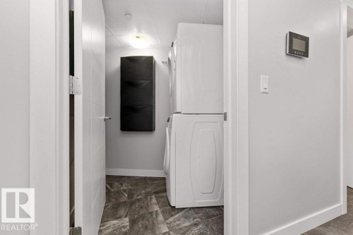 Dedicated laundry area featuring stacked appliances and durable tile flooring - 204 10126 144 Street, Edmonton, AB - Indoor Photo Showing Other Room
