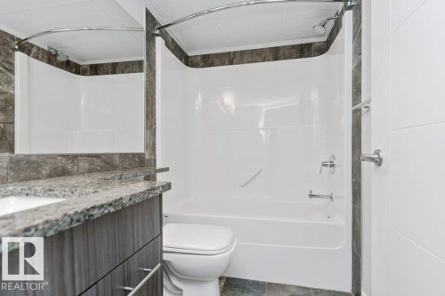 Bathroom featuring a white tub/shower combination with a curved shower rod - 204 10126 144 Street, Edmonton, AB - Indoor Photo Showing Bathroom