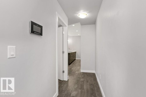 Hallway featuring wood-finish flooring, light gray wall paint, and white trim - 204 10126 144 Street, Edmonton, AB - Indoor Photo Showing Other Room