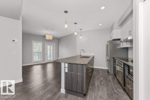 Modern kitchen with a central island featuring a stainless steel sink and pendant lighting - 204 10126 144 Street, Edmonton, AB - Indoor Photo Showing Kitchen With Stainless Steel Kitchen With Upgraded Kitchen