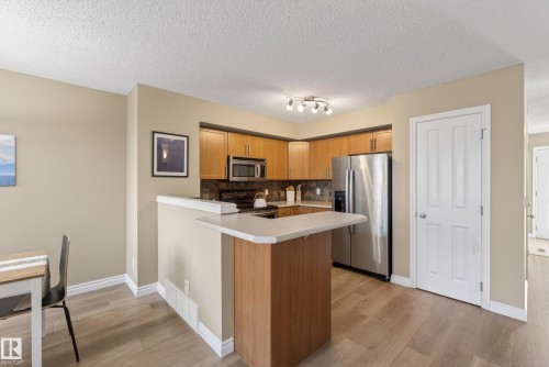 Kitchen area featuring light wood-finish cabinetry, stainless steel appliances, and track lighting - 17 171 Brintnell Boulevard, Edmonton, AB - Indoor Photo Showing Kitchen