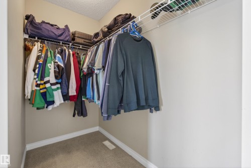 Walk-in closet featuring wire shelving, hanging rods, light beige walls, and carpeting - 17 171 Brintnell Boulevard, Edmonton, AB - Indoor With Storage
