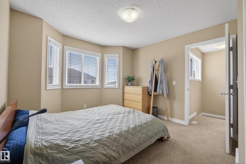 Bay window with multiple white-framed windows, neutral wall color, textured ceiling, and carpeted flooring - 17 171 Brintnell Boulevard, Edmonton, AB - Indoor Photo Showing Bedroom