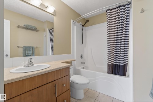 Full bathroom featuring a single vanity with wood-finish cabinetry, a neutral countertop, and an integrated sink - 17 171 Brintnell Boulevard, Edmonton, AB - Indoor Photo Showing Bathroom