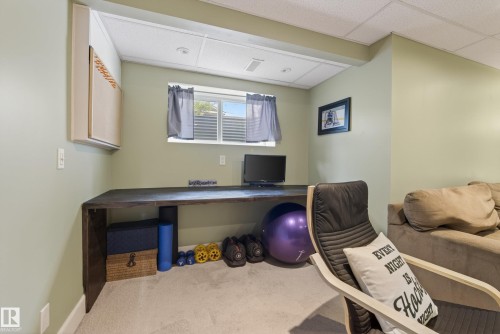 Recessed workspace featuring a built-in wood-finish desk, drop ceiling, and carpeted flooring - 17 171 Brintnell Boulevard, Edmonton, AB - Indoor Photo Showing Other Room