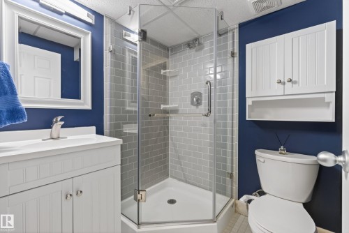 Contemporary bathroom featuring a corner glass-enclosed shower with subway tile surround, a white vanity with integrated sink, and a framed wall mirror - 17 171 Brintnell Boulevard, Edmonton, AB - Indoor Photo Showing Bathroom