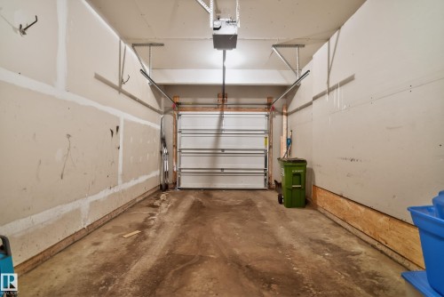 Garage interior featuring a concrete floor, an overhead garage door, and visible wall framing - 17 171 Brintnell Boulevard, Edmonton, AB - Indoor Photo Showing Garage