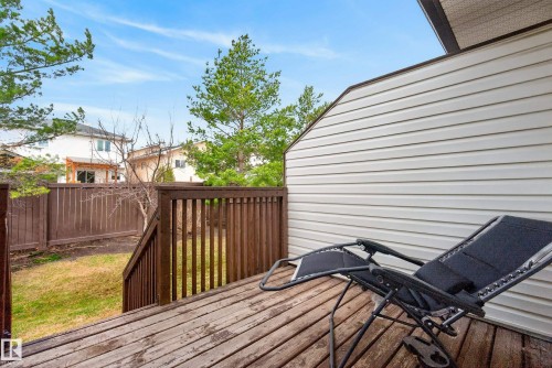 Wood-decked patio with protective railing, siding exterior, and steps descending to a private yard enclosed by a wood fence - 17 171 Brintnell Boulevard, Edmonton, AB - Outdoor With Deck Patio Veranda With Exterior