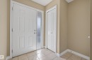 Foyer featuring a paneled entry door with frosted sidelight, bi-fold closet doors, square tile flooring, and neutral wall paint - 17 171 Brintnell Boulevard, Edmonton, AB  - Indoor Photo Showing Other Room 