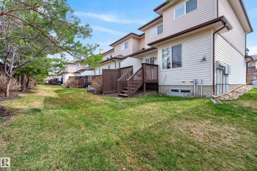 Expansive rear yard featuring green lawn, mature trees, and privacy fencing - 17 171 Brintnell Boulevard, Edmonton, AB - Outdoor