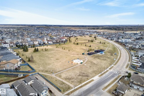 Aerial presentation of a residential neighborhood featuring detached single-family homes, a central park area with walking paths, and multiple play structures - 17 171 Brintnell Boulevard, Edmonton, AB - Outdoor With View