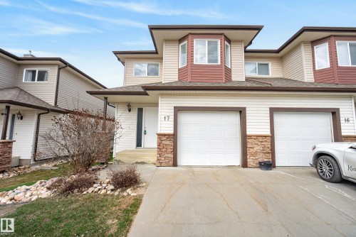 Contemporary multi-level exterior featuring light-colored siding, brown trim, stone accents, multiple garage doors, and bay windows - 17 171 Brintnell Boulevard, Edmonton, AB - Outdoor With Facade