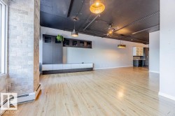 Expansive open-concept room featuring light wood-finish flooring and a dark exposed ceiling - 