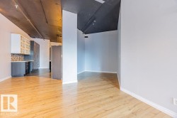 Open concept area featuring light wood-finish flooring, light gray walls, and a dark exposed ceiling - 
