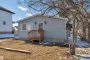 Light blue horizontal siding exterior with a wood entry deck and white window shutters - 4712 49 Street, Calmar, AB  - Outdoor With Exterior 