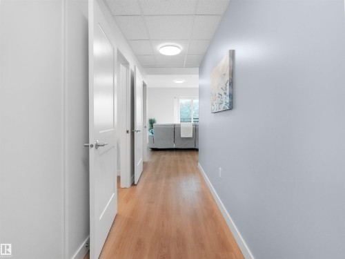 Hallway featuring wood-finish flooring, contemporary white interior doors, and recessed ceiling lighting - 403 10115 88 Avenue, Edmonton, AB - Indoor Photo Showing Other Room