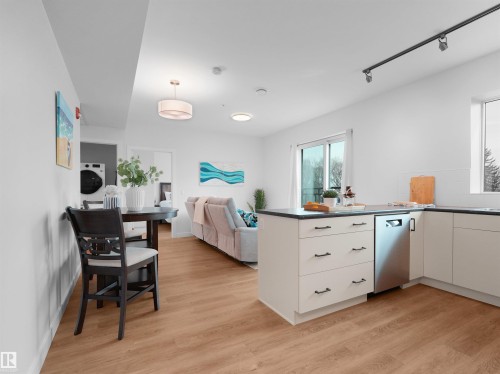 Open-concept living space featuring wood-finish flooring, white walls, and track lighting - 403 10115 88 Avenue, Edmonton, AB - Indoor