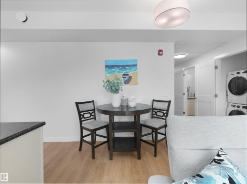 Open-concept living space featuring wood-finish flooring, white walls, and a modern ceiling light fixture - 403 10115 88 Avenue, Edmonton, AB - Indoor Photo Showing Dining Room