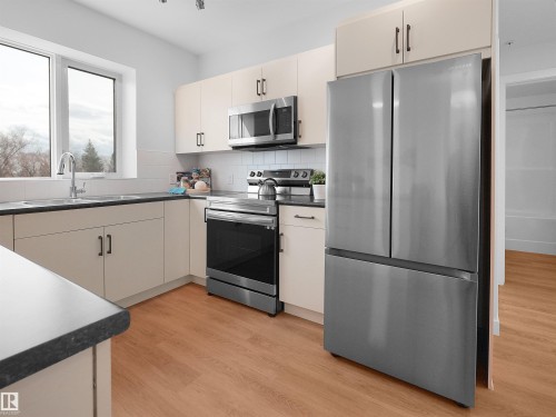 Modern kitchen featuring a stainless steel French door refrigerator, matching oven with stovetop, and microwave - 403 10115 88 Avenue, Edmonton, AB - Indoor Photo Showing Kitchen