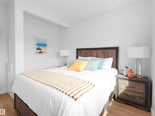 Bedroom featuring wood-finish flooring, a rustic wood-panel headboard, and a matching two-drawer nightstand - 403 10115 88 Avenue, Edmonton, AB - Indoor Photo Showing Bedroom