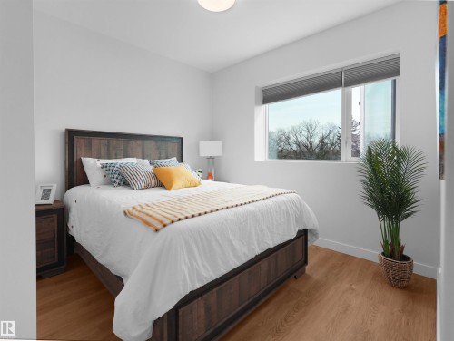 Bright bedroom featuring wood-finish flooring, a large window with privacy blinds, and a flush-mount ceiling light - 403 10115 88 Avenue, Edmonton, AB - Indoor Photo Showing Bedroom