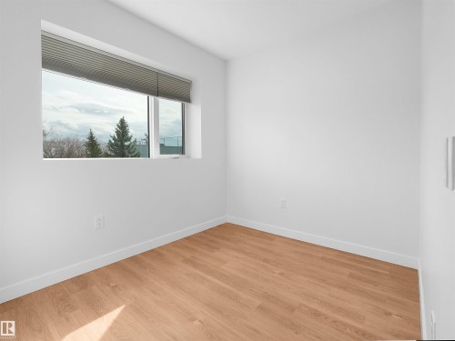 Room featuring wood-finish flooring, crisp white walls, and a large horizontal window with integrated blinds - 403 10115 88 Avenue, Edmonton, AB - Indoor Photo Showing Other Room