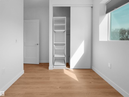 Light wood-finish flooring complements the bright white walls and trim - 403 10115 88 Avenue, Edmonton, AB - Indoor Photo Showing Other Room